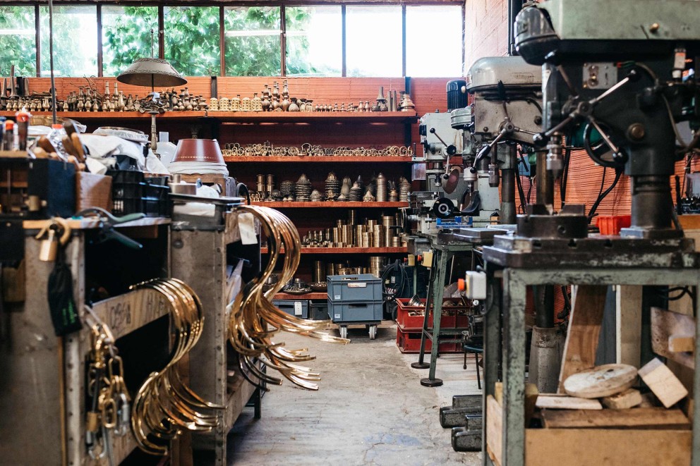 
				Das Atelier von Kronleuchterhersteller Régis Mathieu: ockerrote Wände, Werkbänke, Leuchterteile und Werkzeuge.

			
