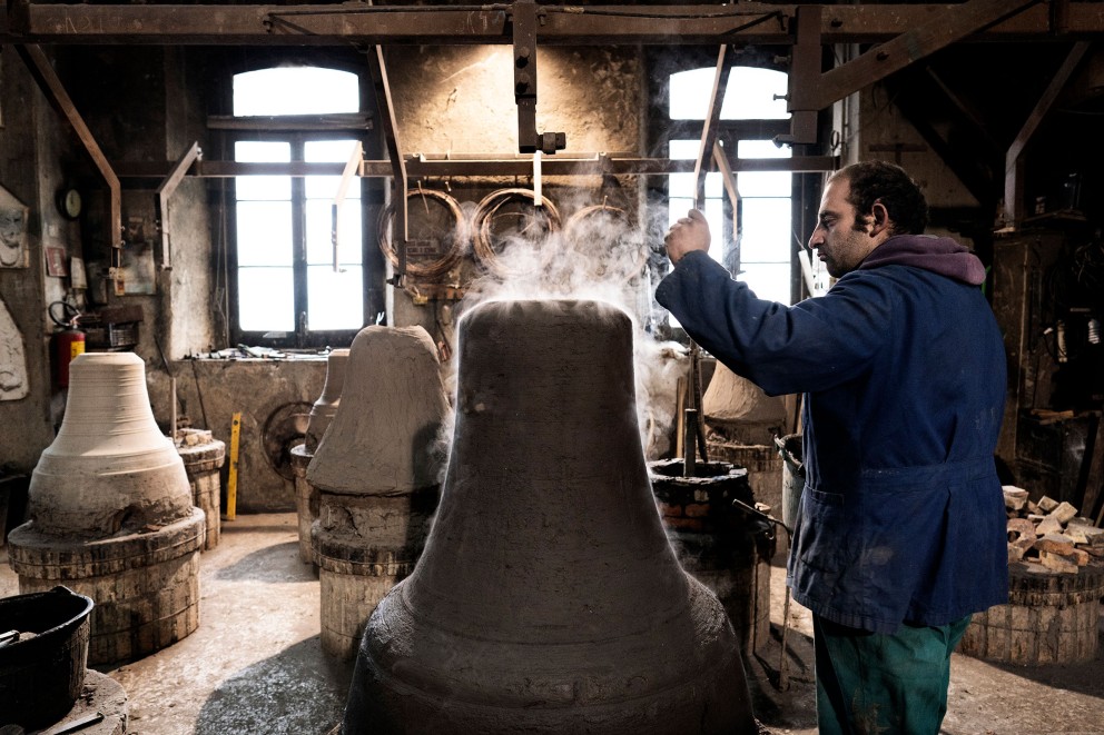 
				Prüfender Blick von Pasquale der Glockengiesserei Marinelli: Mit diesem Tonmodel wird später eine Glocke gegossen. Im Inneren der Tonmodeln verströmt Kohle Wärme zum Trocknen und Rauch

			