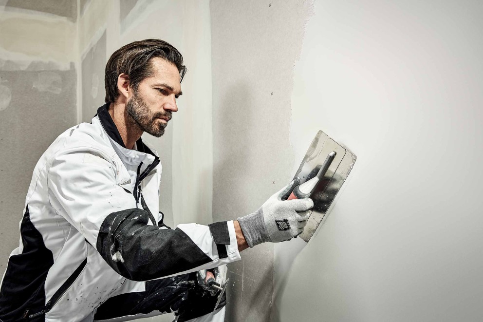 Mann beim verspachteln einer Wand mit dem RAUTNER Flächenspachtel
