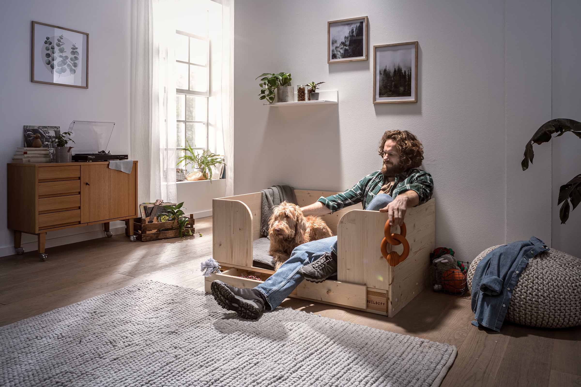 Heller Wohnraum mit Mann und Hund in einem Holz Hundebett mit Schublade