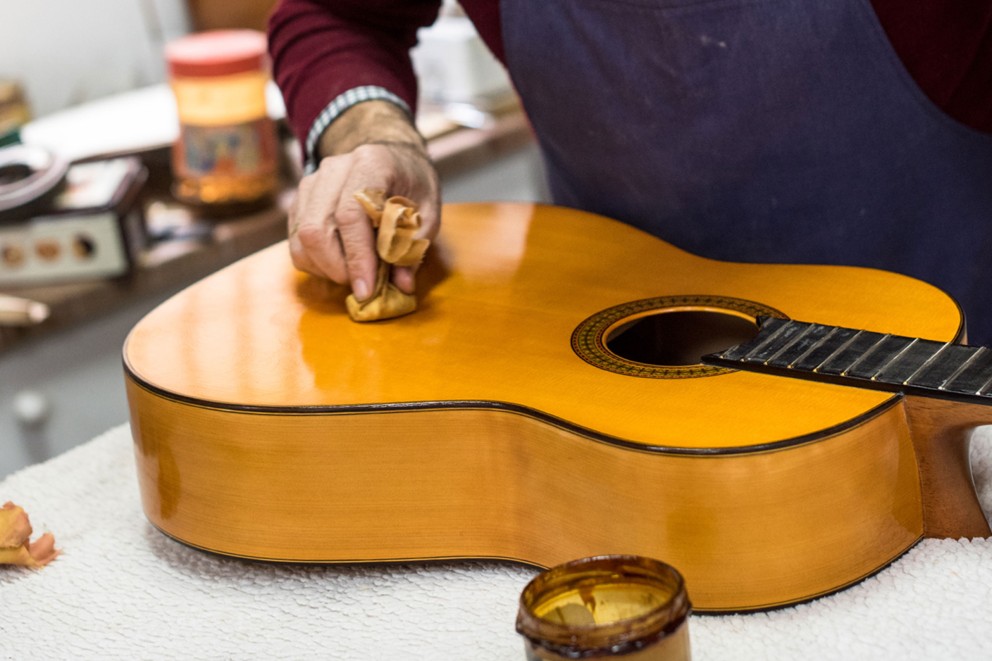 
				José Rodríguez Peña, fabricant de guitares, dessine des cercles de vernis sur le corps de la guitare avec un tampon.

			