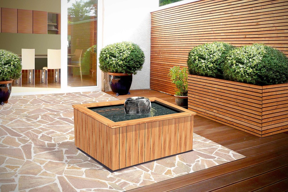 
				Quadratischer Terrassenteich aus Holz mit Springbrunnen auf einer Natursteinterrasse.

			