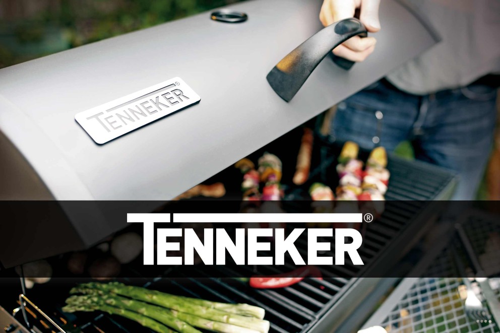 Eine Person öffnet den Deckel eines Tenneker Grills, auf dem Gemüse und Fleisch liegen.