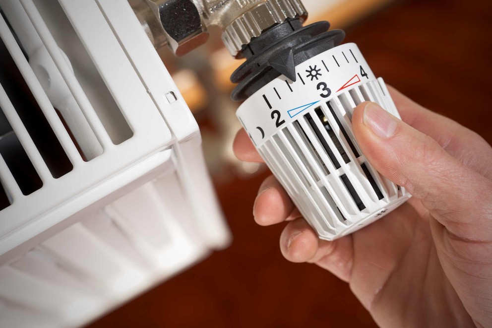 Gros plan d'un thermostat de radiateur ajusté par une main