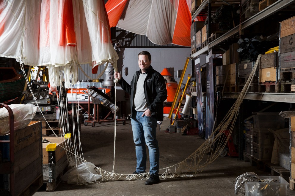 Un homme se tient dans un entrepôt avec un parachute