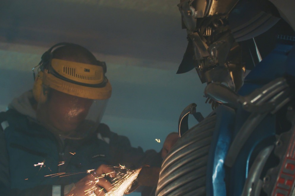 
				Sebastian Kucherski meule une pièce de métal sur le robot Optimus Prime.

			