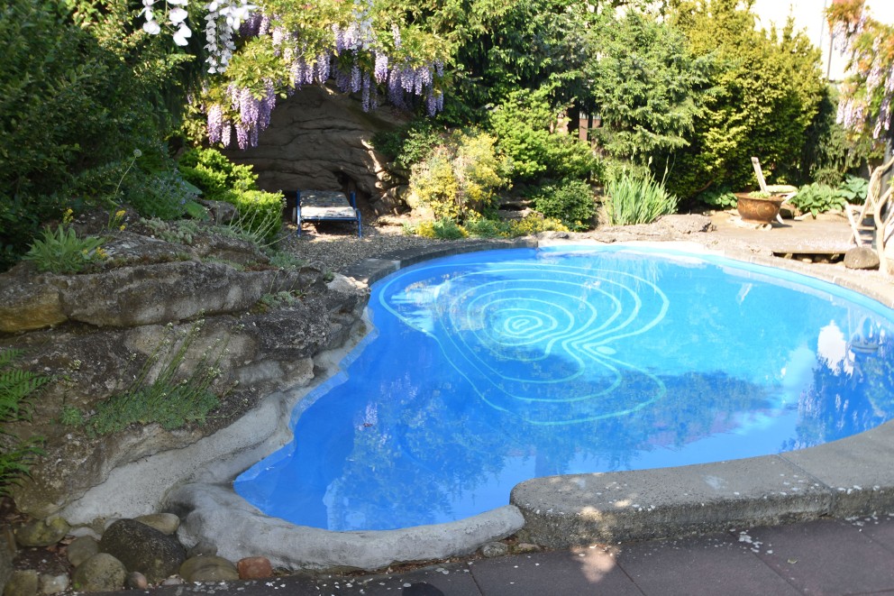 Une piscine et une grotte s'ajoutent au bassin de baignade tout en longueur et son pont: le jardin de ciment fait 850 m². Une piscine et une grotte s'ajoutent au bassin de baignade tout en longueur et son pont: le jardin de ciment fait 850 m².