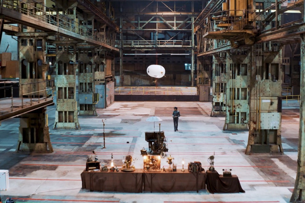 
				Raphaelius fliegt mit einem Helium Luftschiff durch eine grosse Industriehalle

			