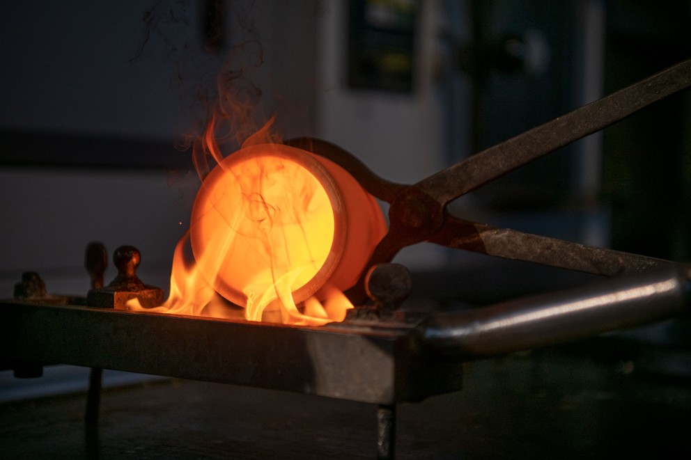
				Bei 1250 Grad schmilzt das Gold. Dann füllt Dieter das flüssige Metall in eine Barrenform, in der es abkühlt und hart wird.

			