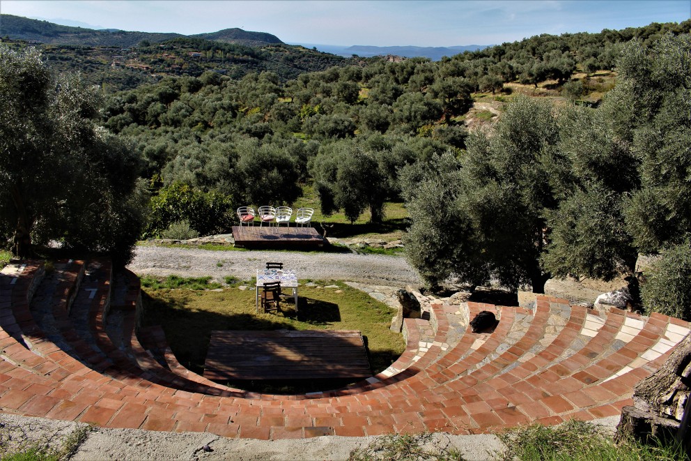Amphitheater mit Ziegelstufen und Blick auf eine bewaldete Landschaft mit Tischen und Stühlen
