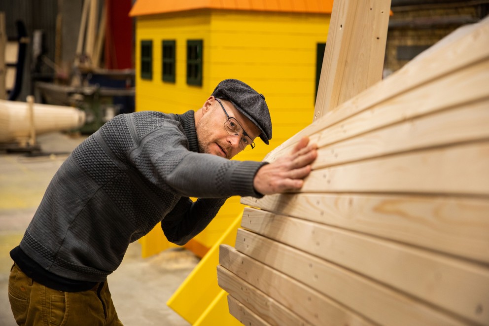 Un homme examine une cabane en bois dans un atelier.