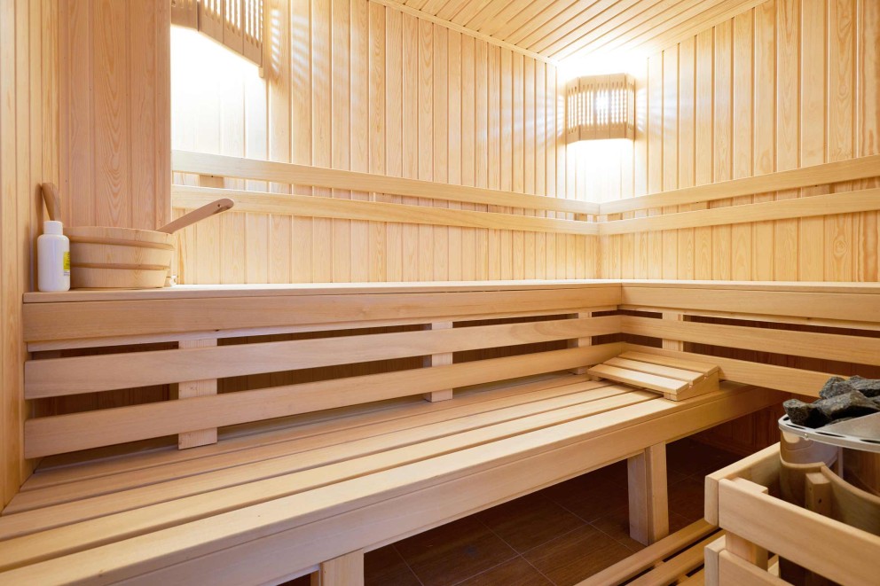 Sauna en bois clair avec bancs, mur en bois et accessoires de sauna