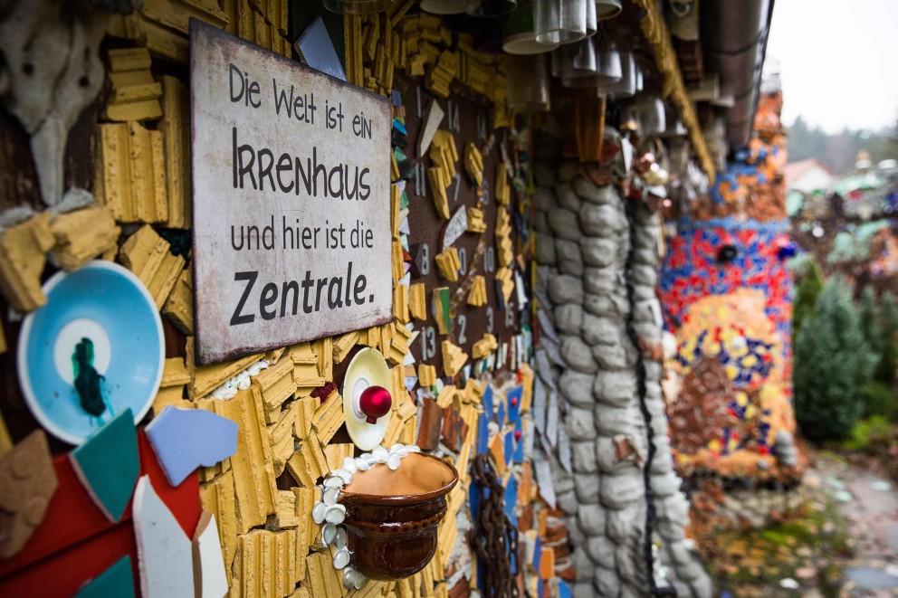 
				Un panneau est accroché sur la façade du château Hundertwasser Lilllliput: «Le monde est un asile de fous et vous vous trouvez dans le bureau central».

			
