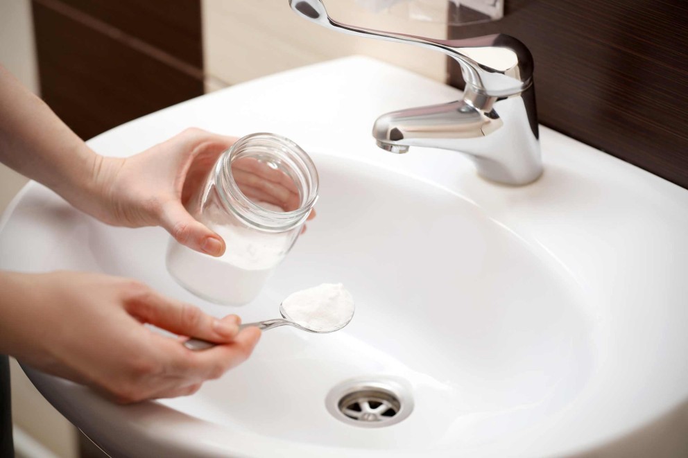 Une femme avec un verre de poudre à lever devant un lavabo Une femme avec un verre de poudre à lever devant un lavabo