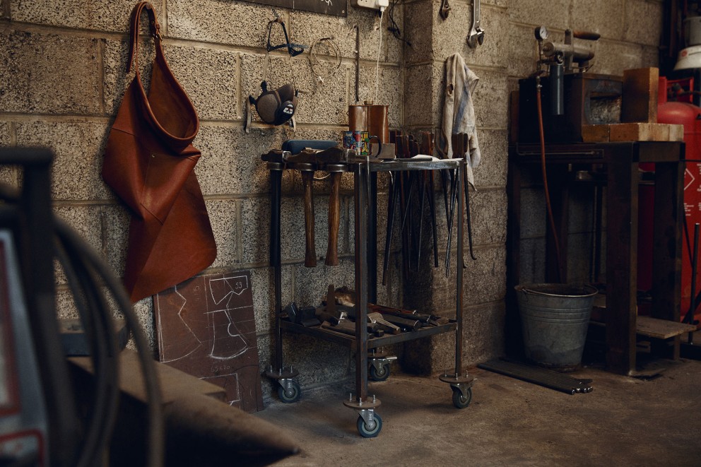 Eine dicke Lederschürze schützt vor Funken und Stahlsplittern. Daneben eine Tafel mit Umrissen von Axtklingen. Eine dicke Lederschürze schützt vor Funken und Stahlsplittern. Daneben eine Tafel mit Umrissen von Axtklingen.