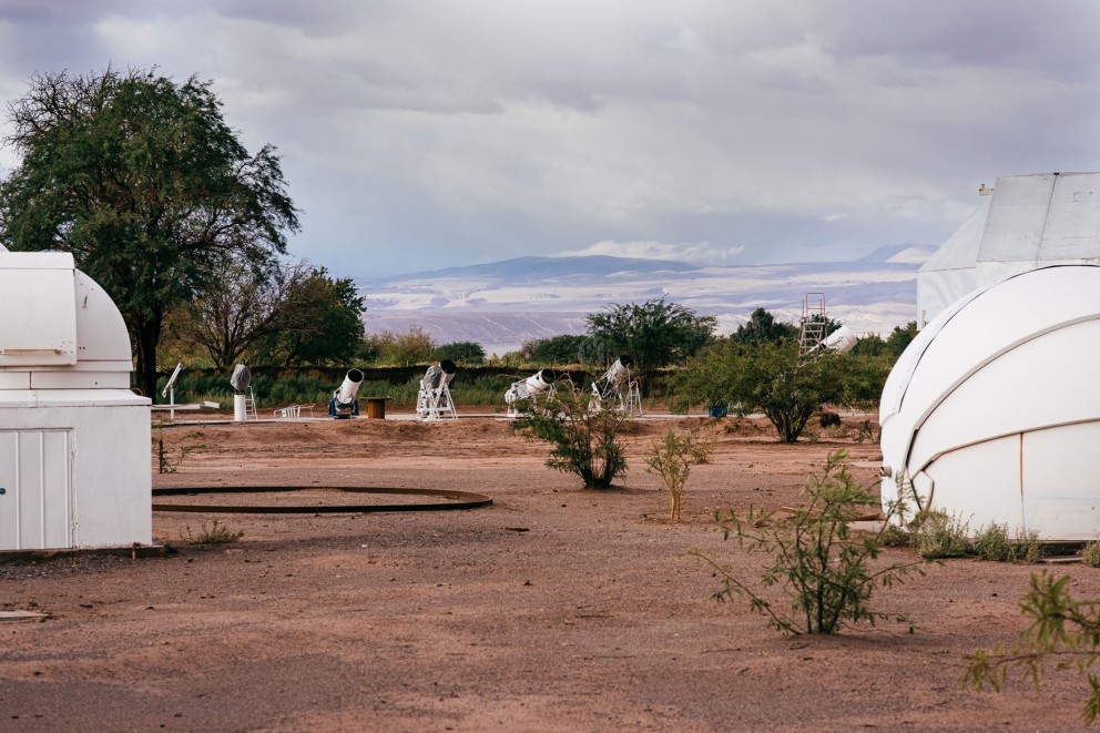 
				Dans le désert d&lsquo;Atacama, devant un panorama des Andes, Alain Maury a installé des coupoles d&lsquo;observation météorologique avec des télescopes automatiques pour ses visiteurs du monde entier, derrière, le télescope construit en grande partie de ses propres mains.

			