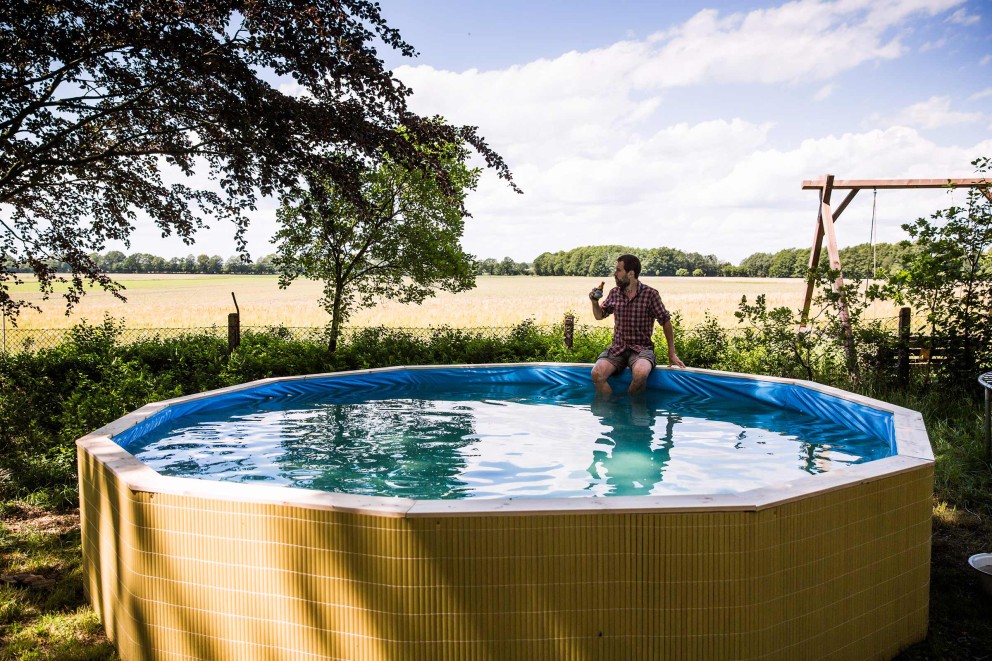 Notre auteur Sascha Borée assis au bord de la piscine qu'il a construite lui même, les pieds dans l'eau fraîche, le regard sur l'horizon. Notre auteur Sascha Borée assis au bord de la piscine qu'il a construite lui même, les pieds dans l'eau fraîche, le regard sur l'horizon.