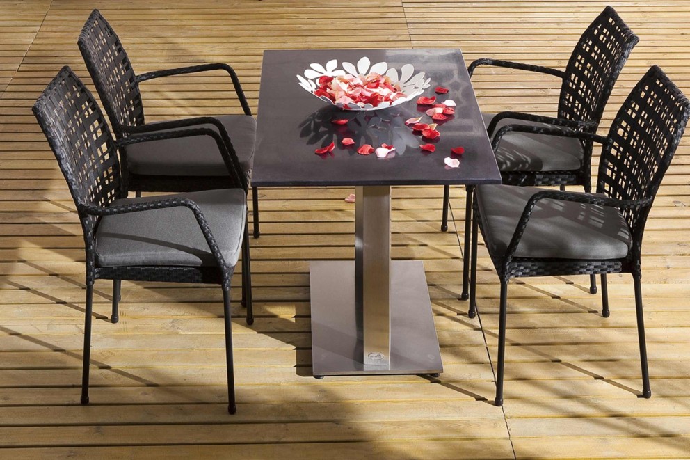 Gartentischgruppe mit vier Rattansesseln und einem Tisch mit einer Schale mit Blütenblättern