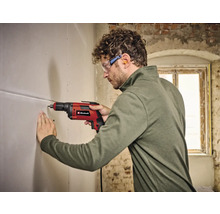 Un homme perce un trou dans un mur avec une perceuse Einhell.