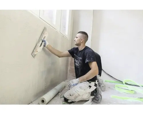 Handwerker beim Verputzen einer Wand mit einer Glättkelle