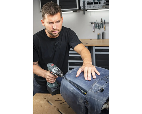 Un homme utilise une visseuse sans fil pour des travaux de réparation sur un composant.