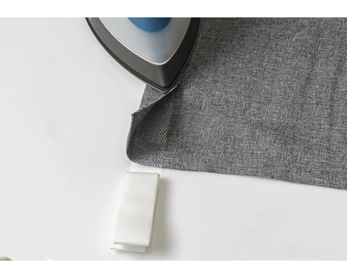 Fer à repasser sur tissu gris avec bande thermocollante