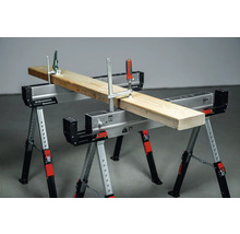 Zwei verstellbare Werkzeugböcke mit einer Holzplanke, die mit Schraubzwingen befestigt ist