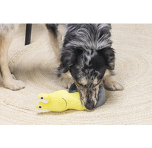 Un chien joue avec un jouet pour chien en forme d''escargot jaune sur un tapis.