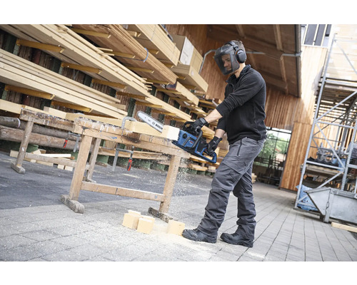 Homme avec visière de protection coupant du bois avec une scie Bosch