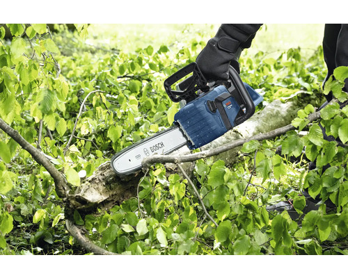 Une personne coupe une branche avec une tronçonneuse Bosch.