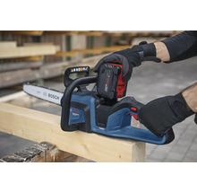 Tronçonneuse à batterie sur une planche en bois avec batterie insérée.