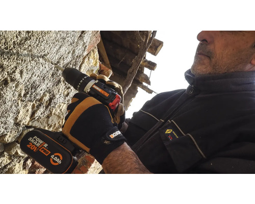 Ein Mann bohrt mit einem Akku-Bohrschrauber ein Loch in eine Steinwand.