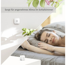 Szene eines Schlafzimmers mit einem Raumklimasensor an der Wand und auf dem Nachttisch neben einer schlafenden Frau