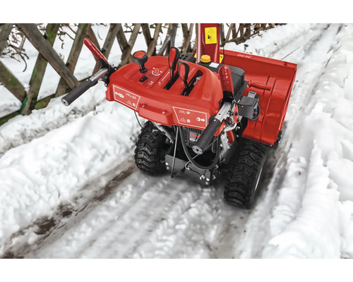 Fraise à neige rouge sur un chemin enneigé.
