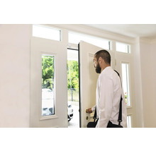 Mann öffnet eine weiße Haustür mit Fenster