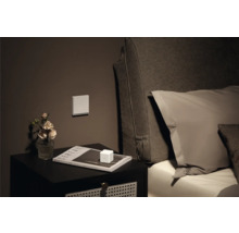 Table de chevet avec décoration, interrupteur au mur et lit en arrière-plan
