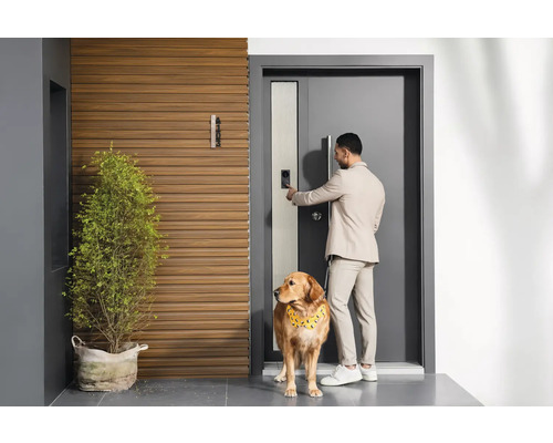 Homme avec un chien devant la porte d''entrée avec serrure numérique