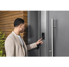 Un homme utilise une porte d''entrée moderne avec interphone et caméra