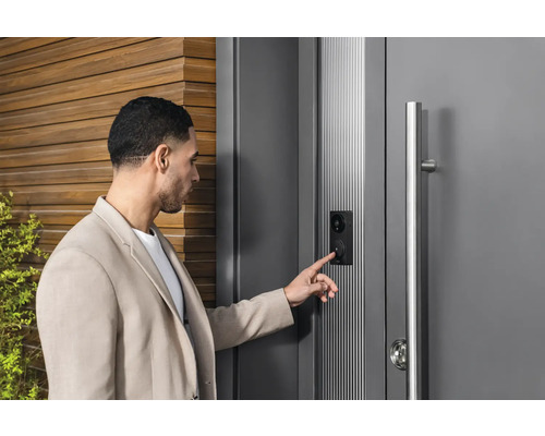 Un homme utilise une porte d''entrée moderne avec interphone et caméra