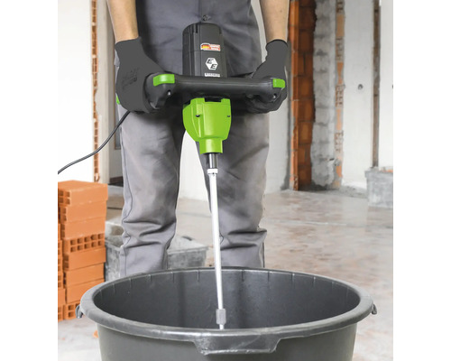 Personne utilisant un mélangeur à mortier dans un seau.