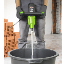 Un homme utilise un mélangeur à mortier dans un seau sur un chantier de construction.