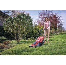 Frau bedient einen roten Rasenmäher im Garten.