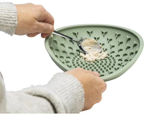 Une personne remplit une gamelle pour animaux de compagnie avec une cuillère