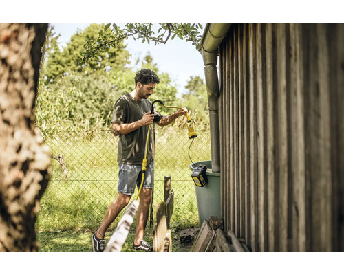 Un homme utilise une pompe de citerne Kärcher pour arroser le jardin.