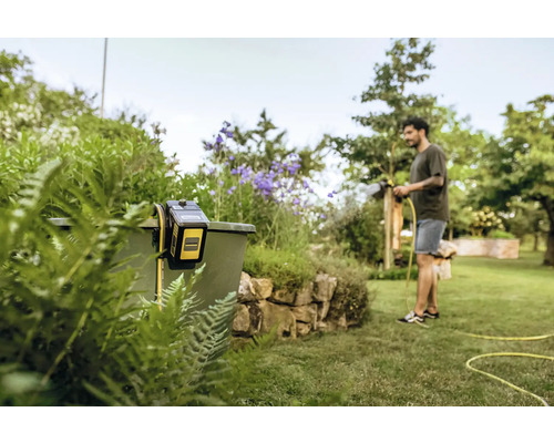 Homme arrosant le jardin avec un système d''irrigation Kärcher fixé à un réservoir
