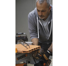 Un homme scie une brique avec une scie de table Worx.
