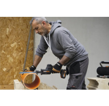 Un artisan coupe un tuyau avec une scie sabre sans fil