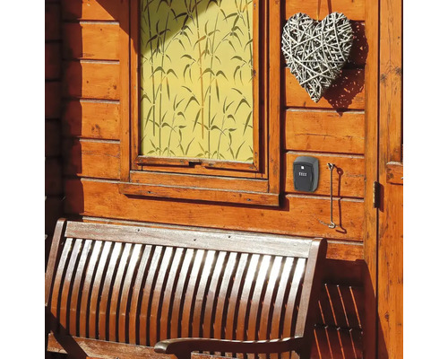 Boîte à clés à code numérique sur un mur en bois à côté d''un banc en bois