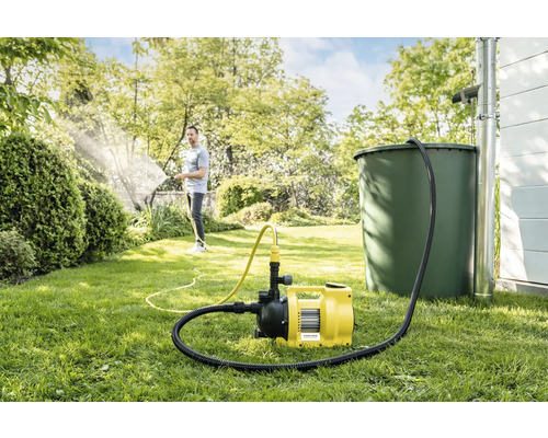 Garten mit Regentonne, Hauswasserwerk und Person beim Bewässern