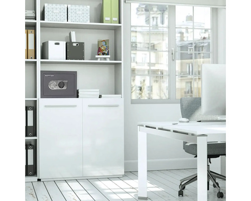 Un bureau lumineux avec une étagère blanche, un bureau et un coffre-fort gris